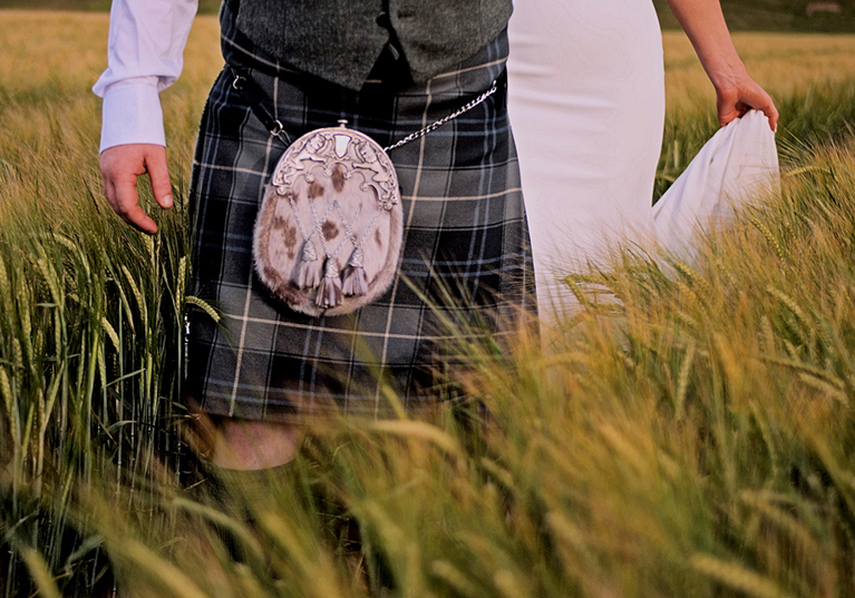 Bride and groom bottom half walking through long grass